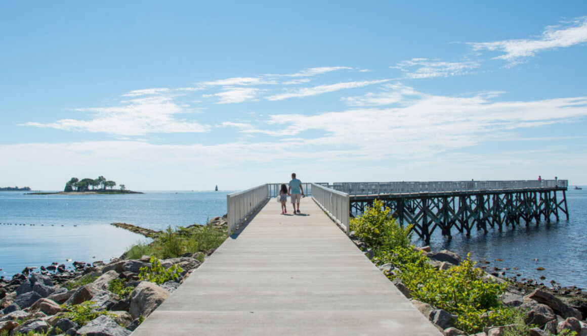 A view down the pier boardwalk on a beautiful summer day by the Long Island Sound at Calf Pasture Beach in Norwalk, Connecticut USA