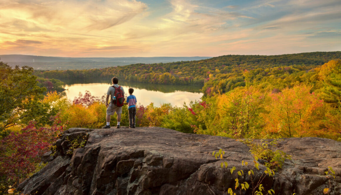 father and son hike to a beautiful overlook in the fall