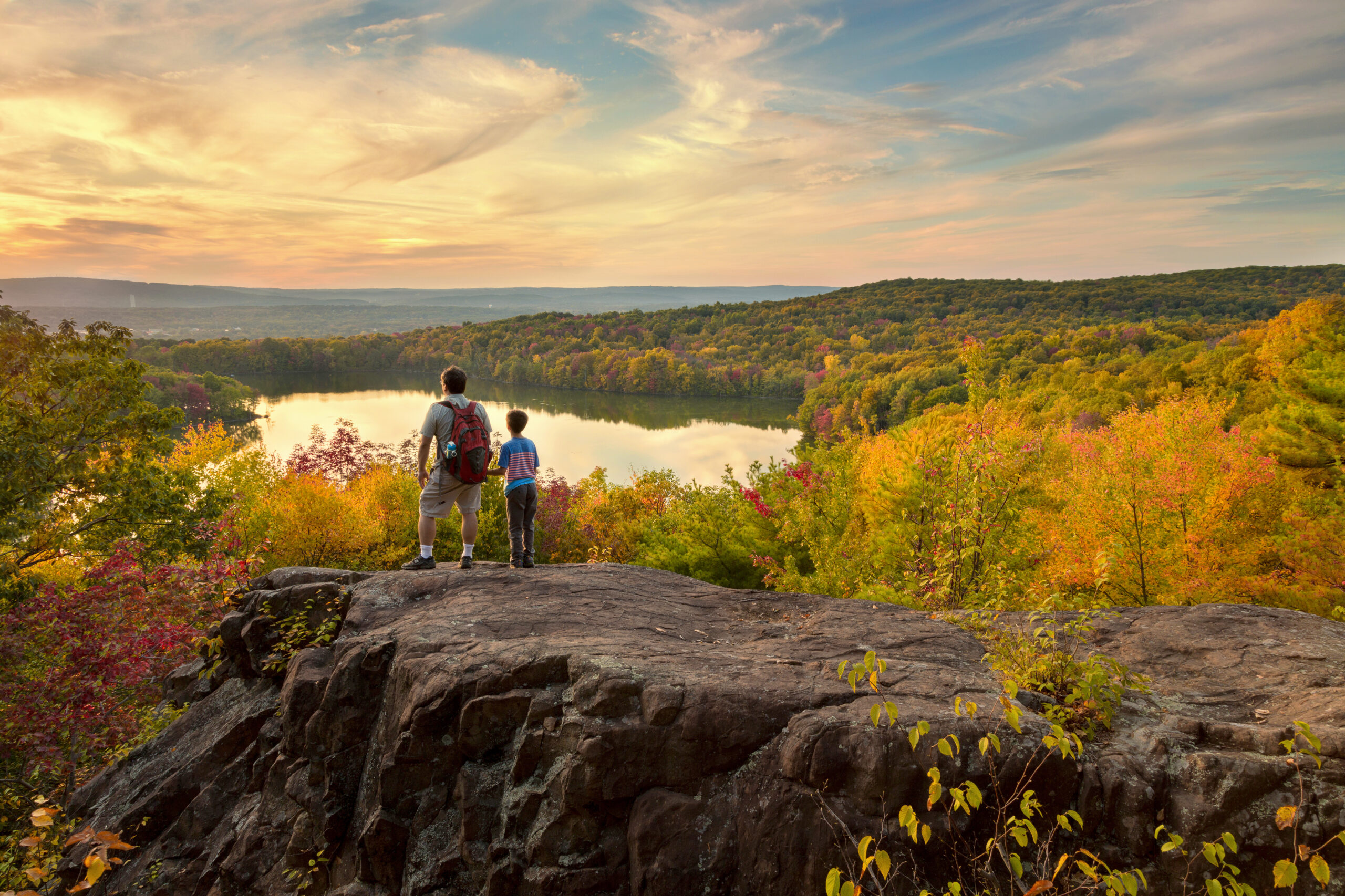 father and son hike to a beautiful overlook in the fall