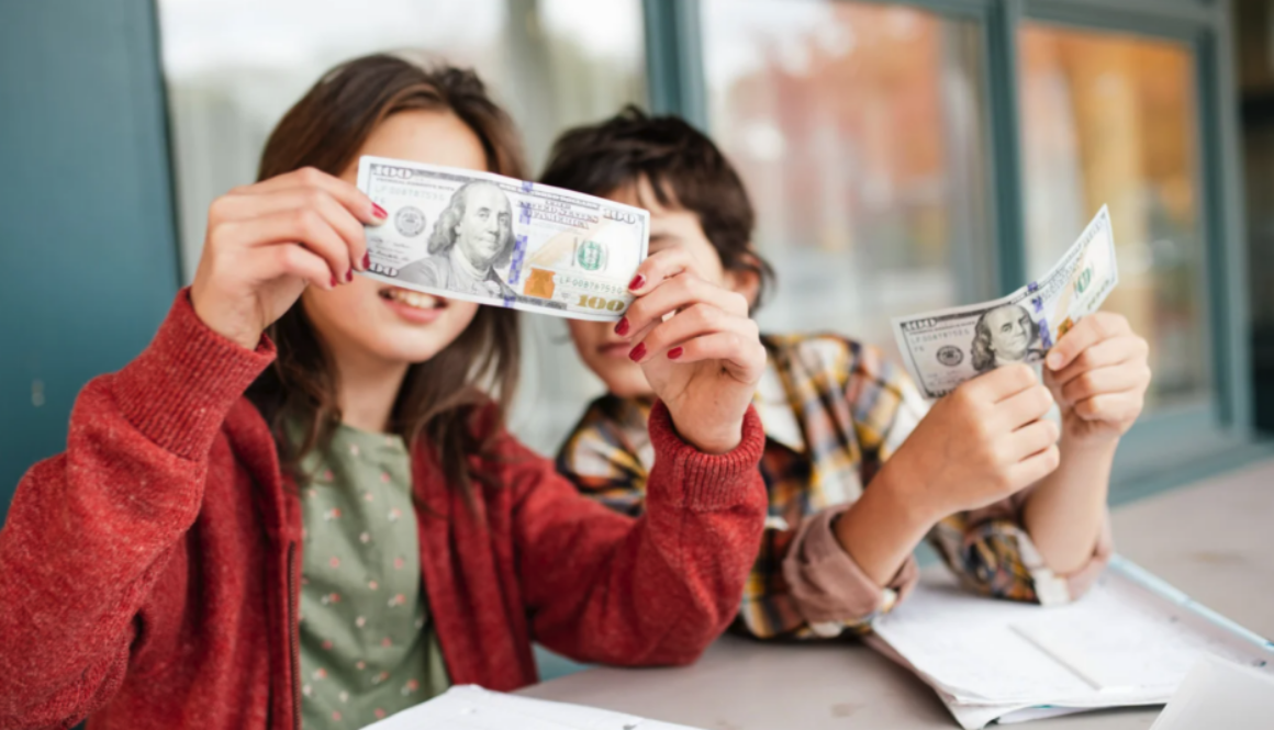 Two children looking at money, representing teaching kids about money from an early age