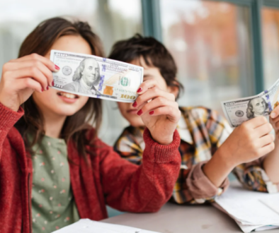 Two children looking at money, representing teaching kids about money from an early age