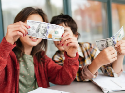 Two children looking at money, representing teaching kids about money from an early age