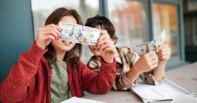 Two children looking at money, representing teaching kids about money from an early age